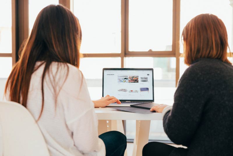 Zwei Frauen reden, während sie auf den Laptop schauen für Ihre neue Firmenwebsite