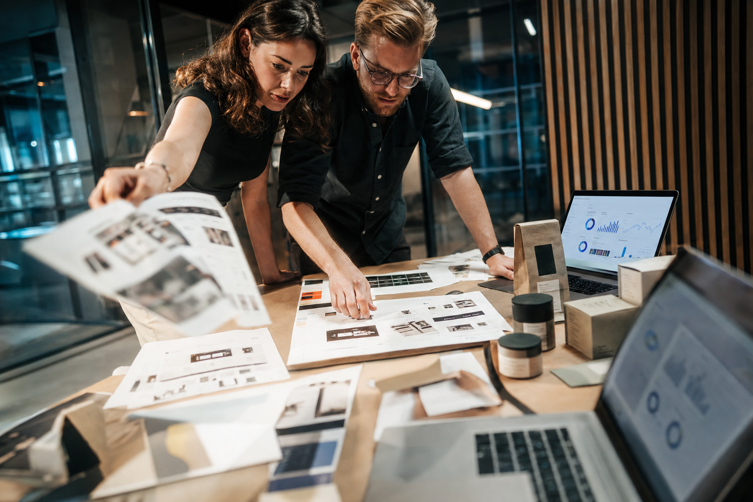 Strategische Planung eines Online-Shop-Relaunchs Zwei Personen planen an einem Tisch den Relaunch eines Online-Shops mit Skizzen, Produktverpackungen und anonymen Analyseansichten.